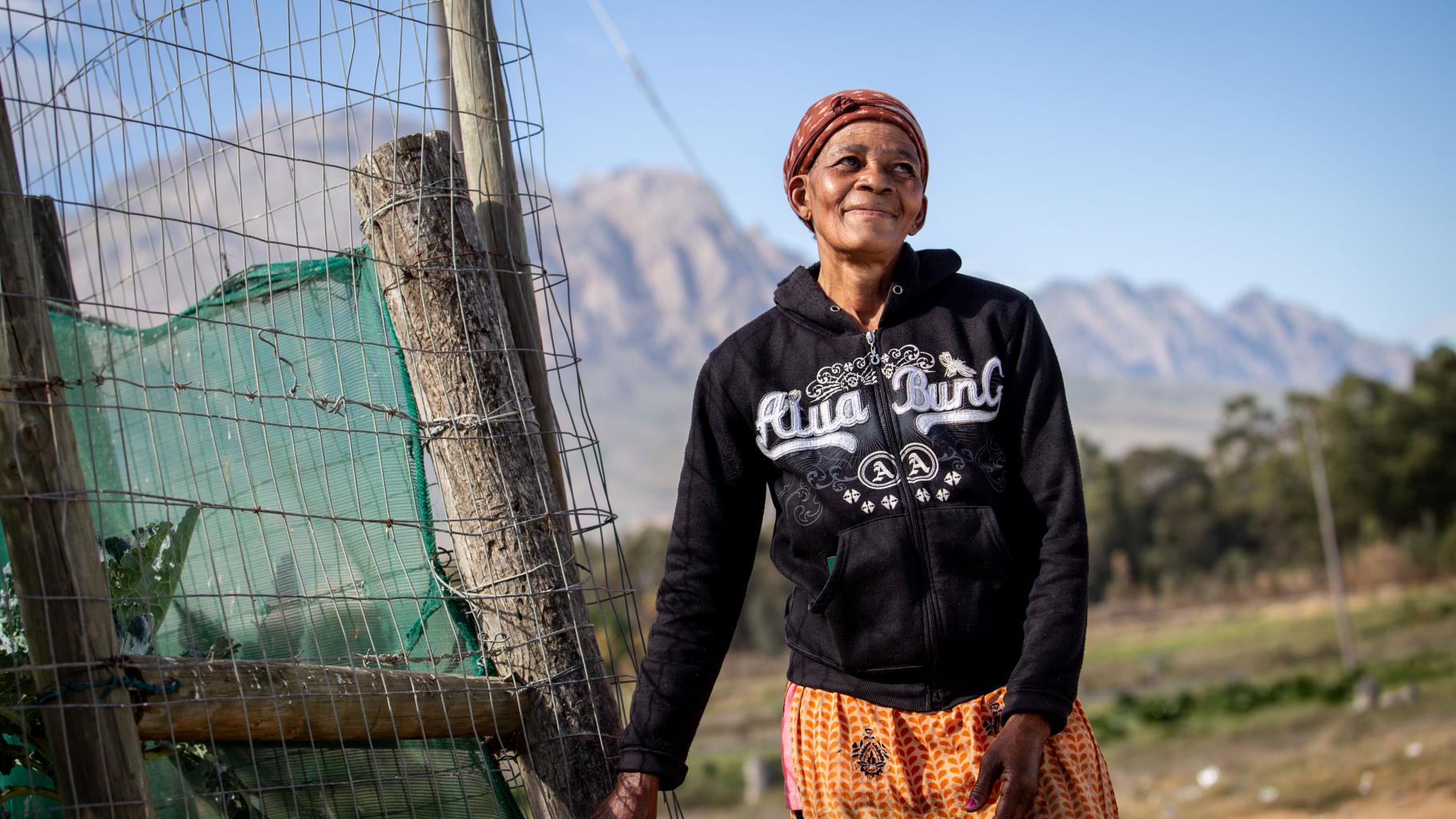 Farmarbeiterin Anna Tshepe steht neben einer abgezäunten Plantage in Wolseley, Südafrika und lächelt