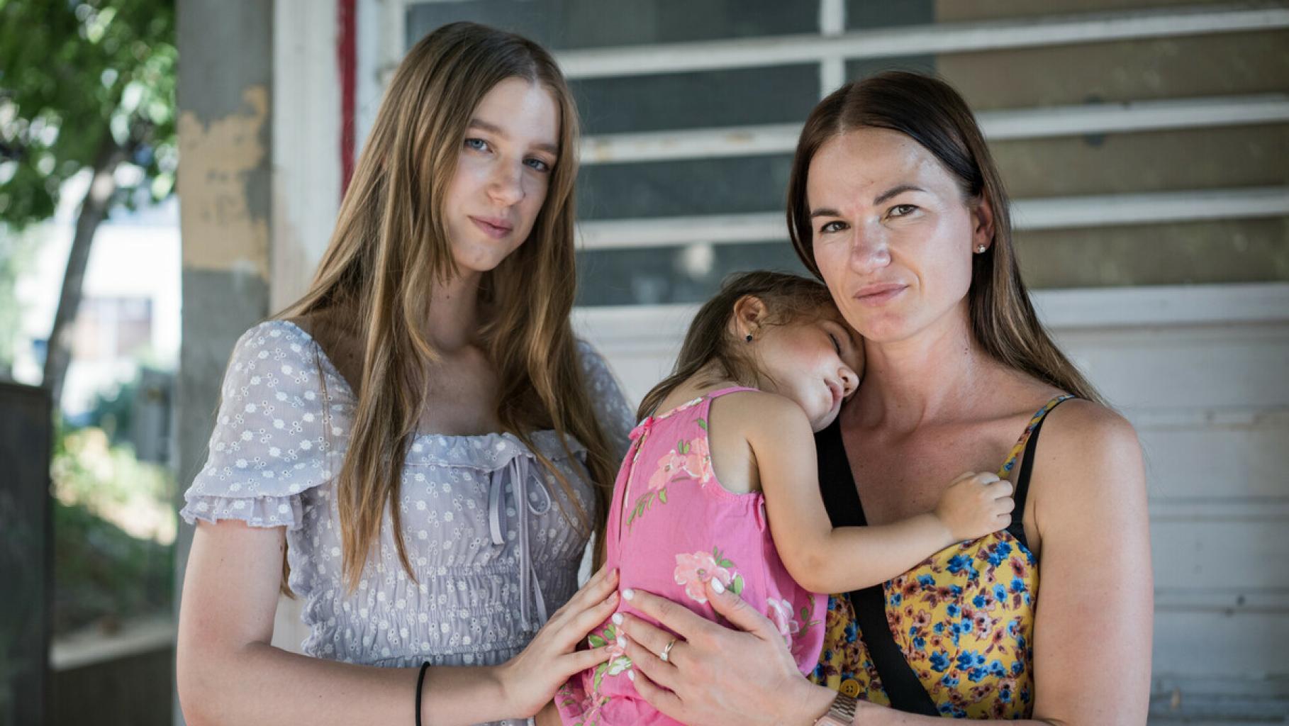Nadiia mit ihren beiden Töchtern Anastasiia* und Melisa*. Mutter Nadiia hält ihre kleinere, schlafende Tochter Anastasiia* auf dem Arm. Die drei sind aus der Ukraine nach Rumänien geflohen und haben sich gerade vom eLiberare-Team dazu beraten lassen, wie sie sich auf ihrer weiteren Reise vor Menschenhandel schützen können.