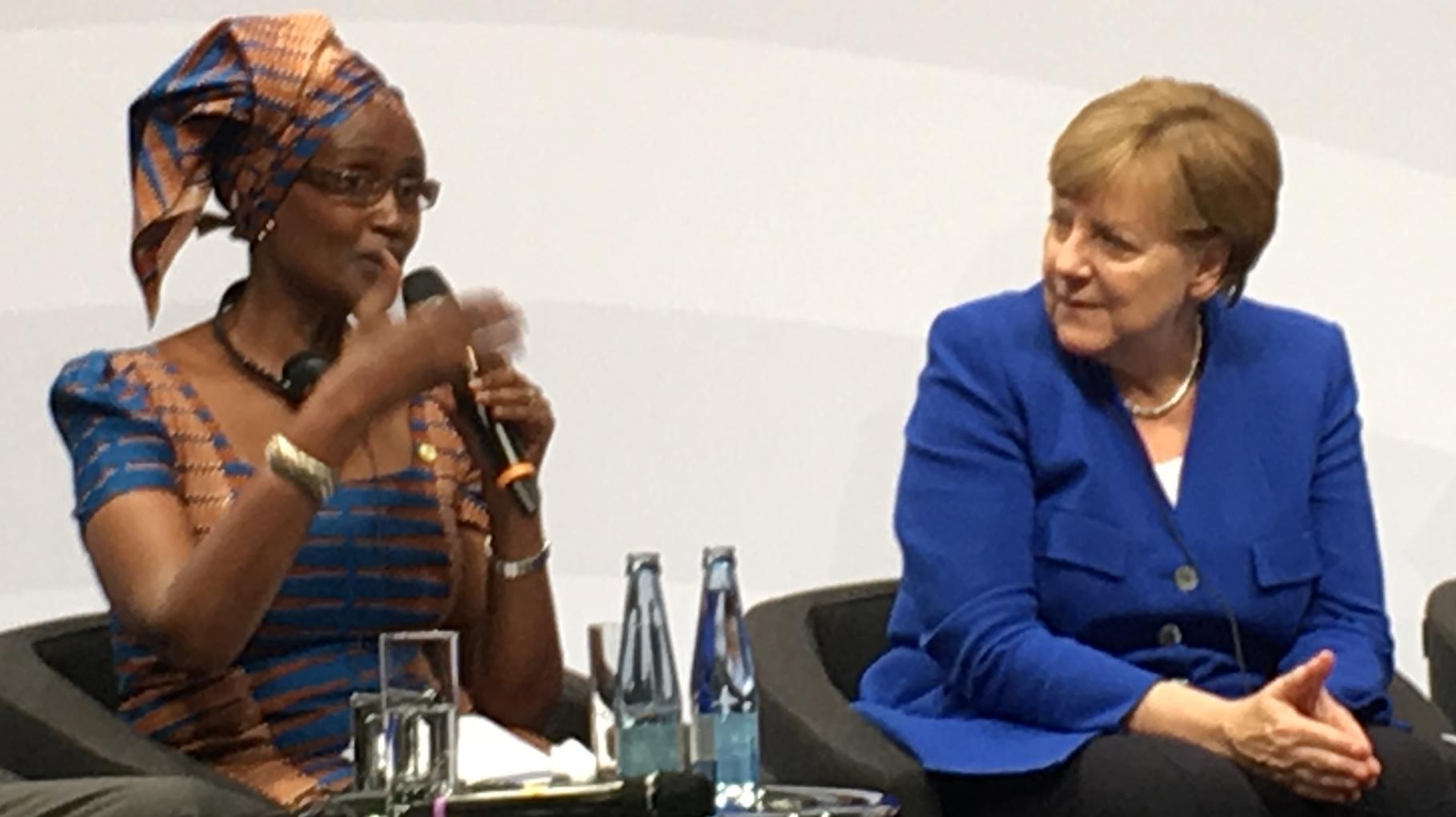 Winnie Byanyima spricht neben Angela Merkel bei einer Podiumsdiskussion.