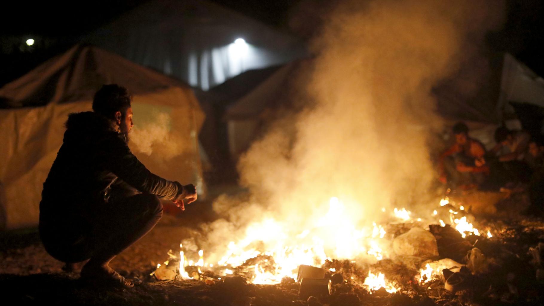 Geflüchteter in Griechenland vor einem Feuer