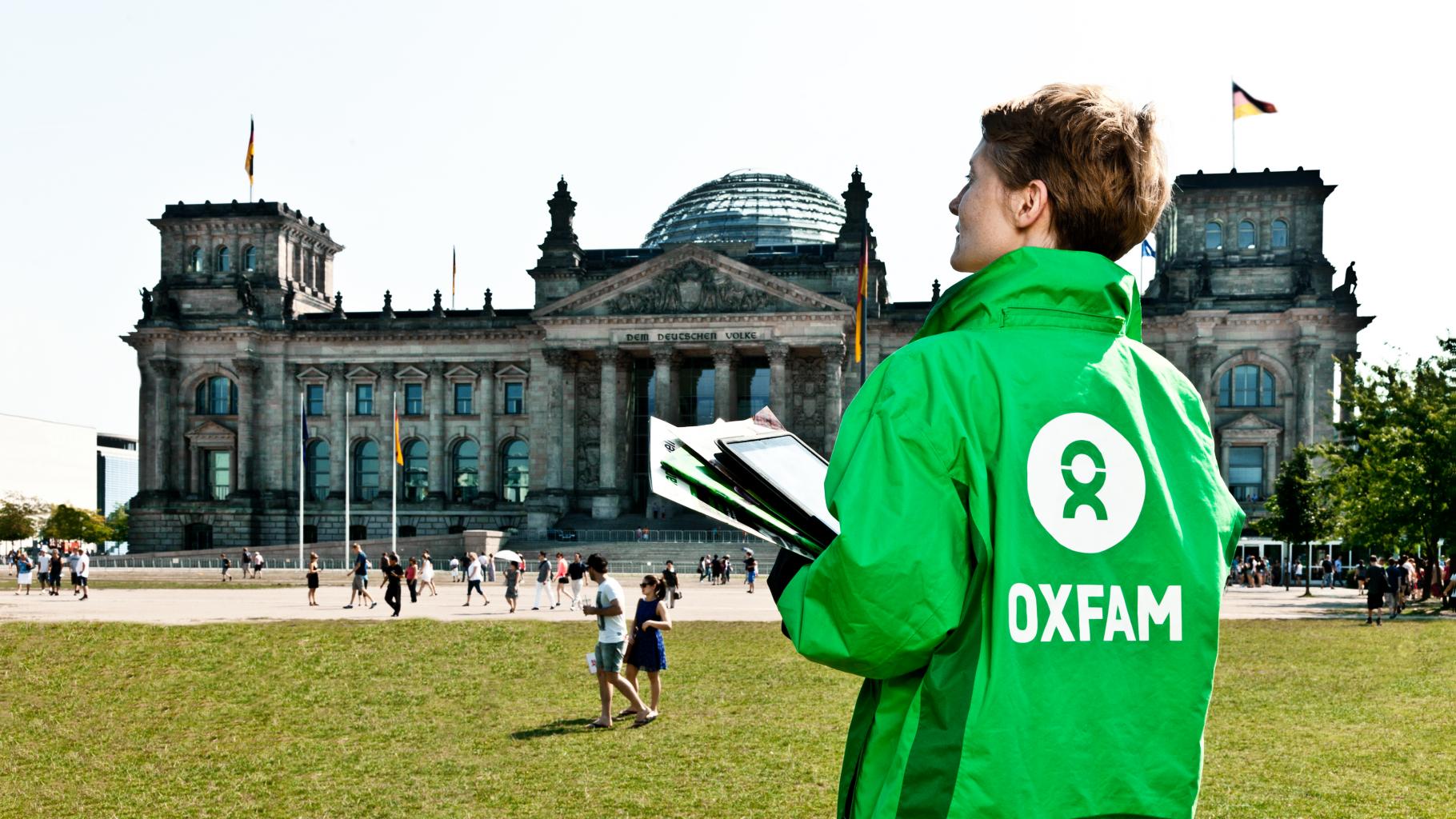 Eine Aktivistin in Oxfam-Jacke steht vor dem Reichstagsgebäude