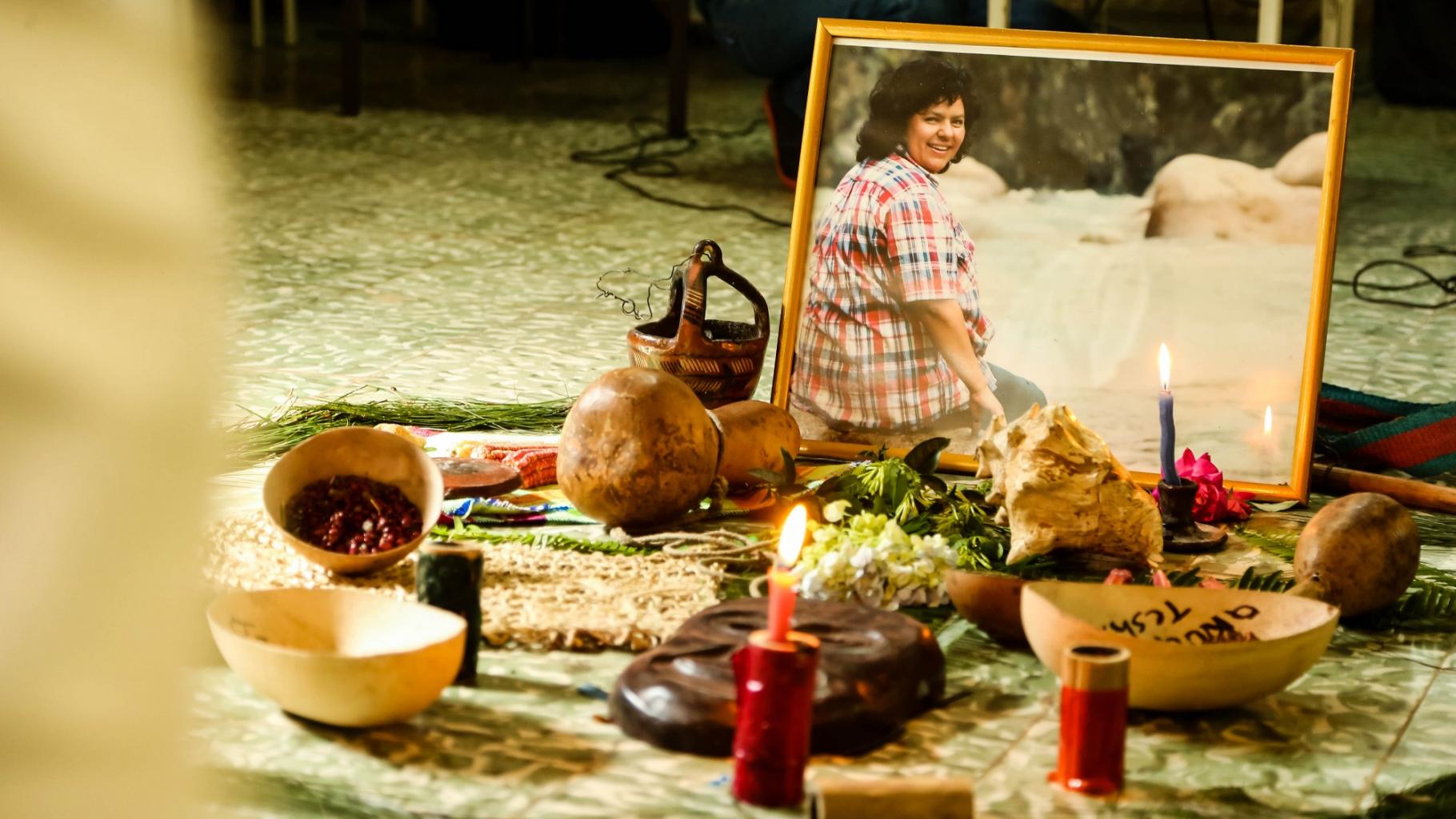 Ein Schrein mit einem kleinen Foto von Berta Cáceres und Kerzen, Blumen, Schalen und anderen kleinen Gegenständen