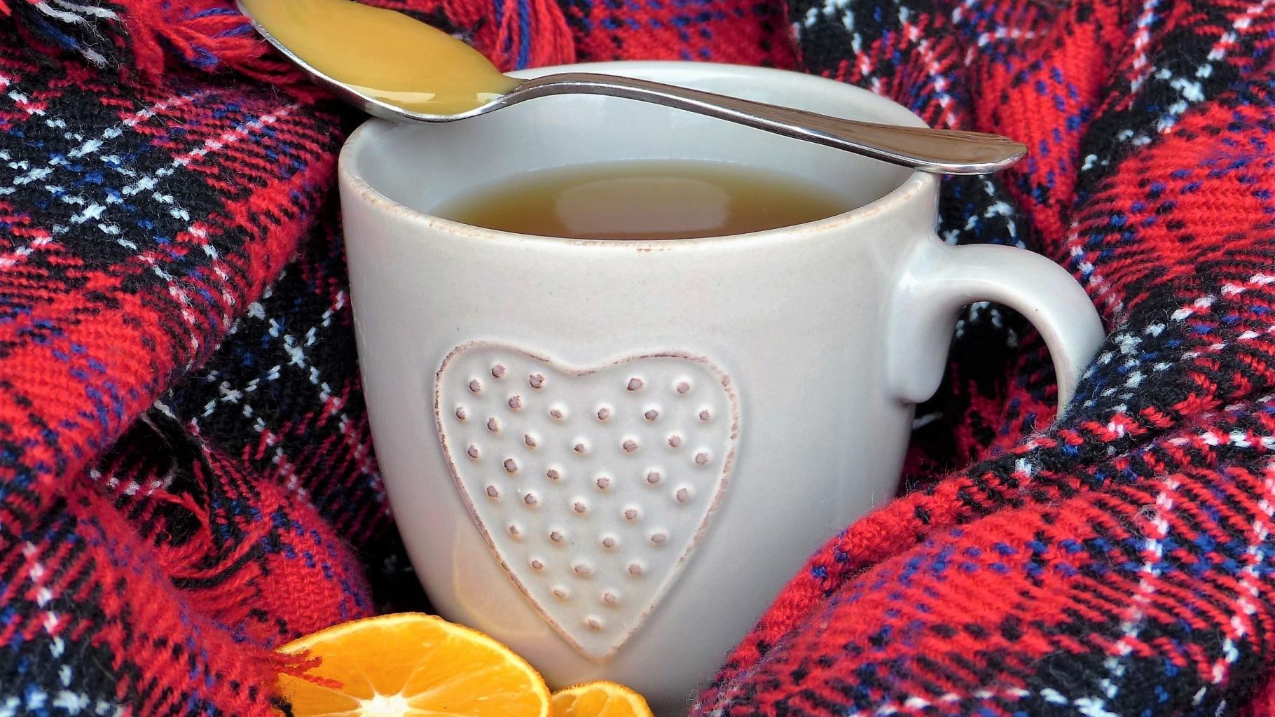 Eine Tasse Tee mit einem Löffel Honig und Orangenscheiben