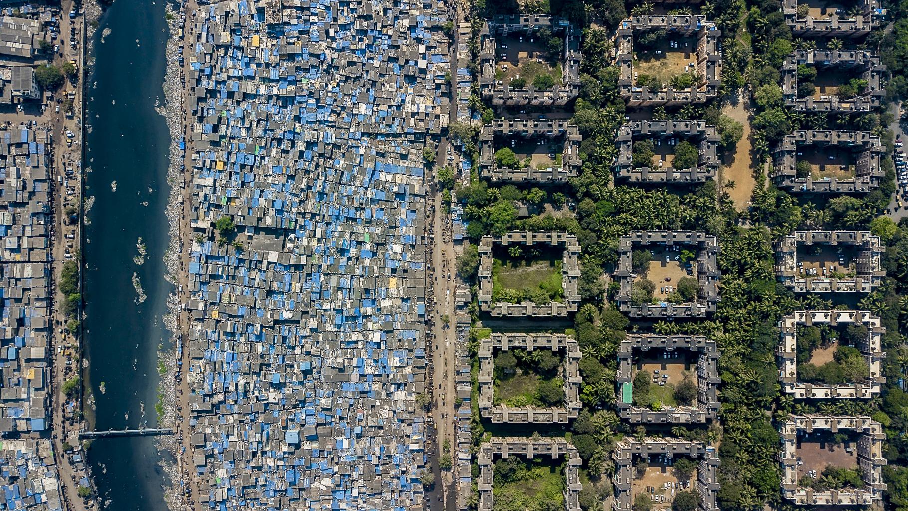 Luftbildaufnahme einer Stadt: Einfache Behausungen auf der einen, Wohnungen Wohlhabender auf der anderen Seite