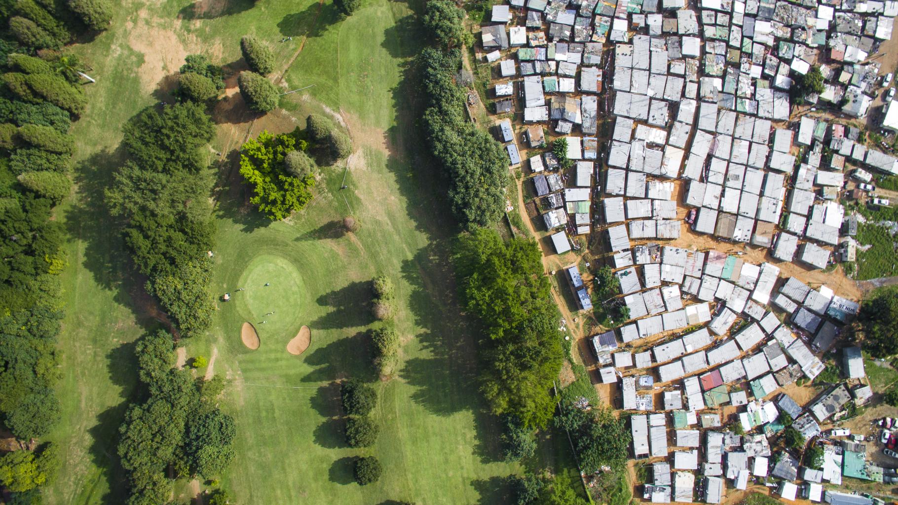 Luftaufnahme: Ein Golfplatz und ein Slum