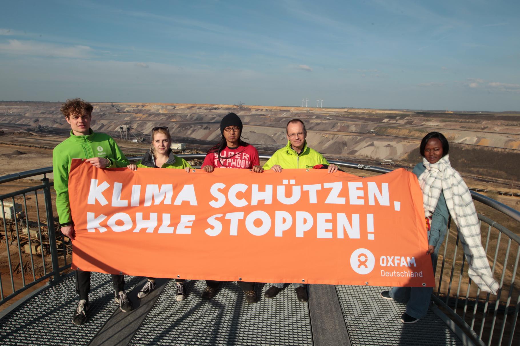 Klimazeug/innen und Vetreter/innen von Oxfam und BUND fordern mit einem Transparent vor dem Braunkohlebau Garzweiler „Klima schützen, Kohle stoppen!”