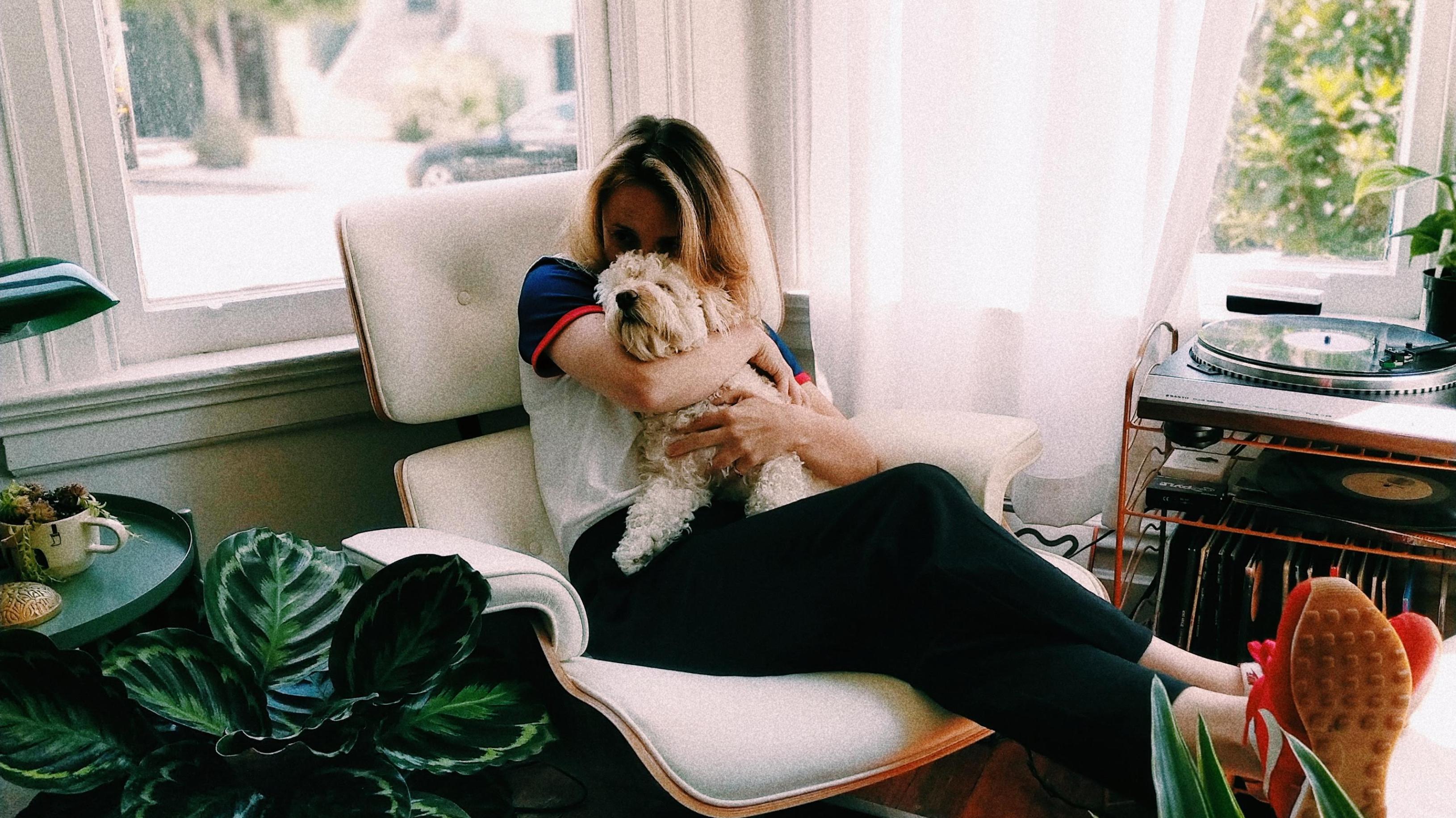 Eine Frau im Relaxsessel umarmt ihren Hund