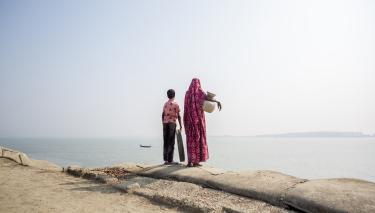 Frau und Kind auf der Suche nach Wasser Eine Mutter steht mit ihrem Kind am Rande einer Küste. Unter dem Arm trägt sie einen Krug zum tranportieren von Wasser.