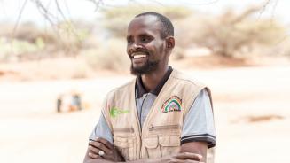 „Ich bin Ibrahim Kabelo. Ich arbeite für das Merti Integrated Development Program (MID-P) als Programm-Manager. MID-P ist eine lokale NRO mit Sitz in Isiolo, Kenia. Wir verteilen in der aktuellen Dürre bedingungslose Bargeldtransfers an besonders bedürftige Familien in Badana und Modogashe. Neben dem Bargeld geben wir auch wichtige Gegenstände des täglichen Bedarfs aus.“ Ibrahim Kabelo schaut freundlich und selbstbewusst in die Ferne.Er trägt eine Weste mit dem Oxfa,-Logo und dem MID-P-Logo.