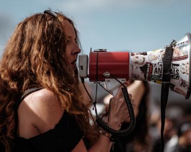 Gemeinsam für mehr Gerechtigkeit und Veränderung. Eine Frau nutzt ein Megaphon auf einer Demo