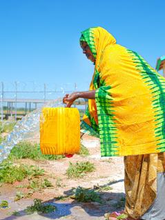 Deka Adan holt Wasser an einer neuen Wasserstelle im Dorf Faramara in Somalia. Eine Frau füllt einen gelben Wasserkanister an einer Wasserleitung.