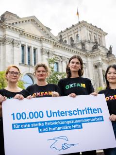 Oxfam Deutschland e.V. und 15 weitere Organisationen haben am 08.09.2026 vor dem Bundestag in Berlin das Ergebnis der gemeinsamen Petition unter dem Motto „Solidarität nicht kaputt sparen“ an die Fraktionsspitzen von CDU/CSU und SPD übergeben. Der Vorsitzende der SPD-Bundestagsfraktion Dr. Matthias Miersch und der stellvertretende Vorsitzende der CDU-/CSU-Bundestagsfraktion Klaus Mack nahmen die rund 100.000 Unterschriften entgegen. Fünf Personen stehen auf einer Treppe vor dem Bundestag und halten ein Schild mit der Aufschrift: 100.000 Unterschriften für eine starke Entwicklungszusammenarbeit und humanitäre Hilfe.