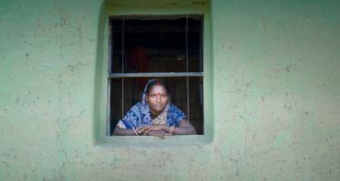 Oxfam setzt sich global für Arbeits- und Frauenrechte ein. Saroda Tati schaut uns freundlich durch ein Fenster an.