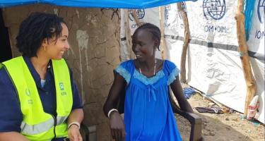 Die Direktorin von Oxfam in Afrika, Fati N'zi-Hassane und Nyaguka Jiek unterhalten sich. Die Direktorin von Oxfam in Afrika, Fati N'zi-Hassane (links, trägt ein dunkelblaues Hemd und eine neongelbe Weste) und Nyaguka Jiek (rechts, trägt ein blaues Kleid) sitzen auf weißen Plastikstühlen nebeneinander und unterhalten sich.